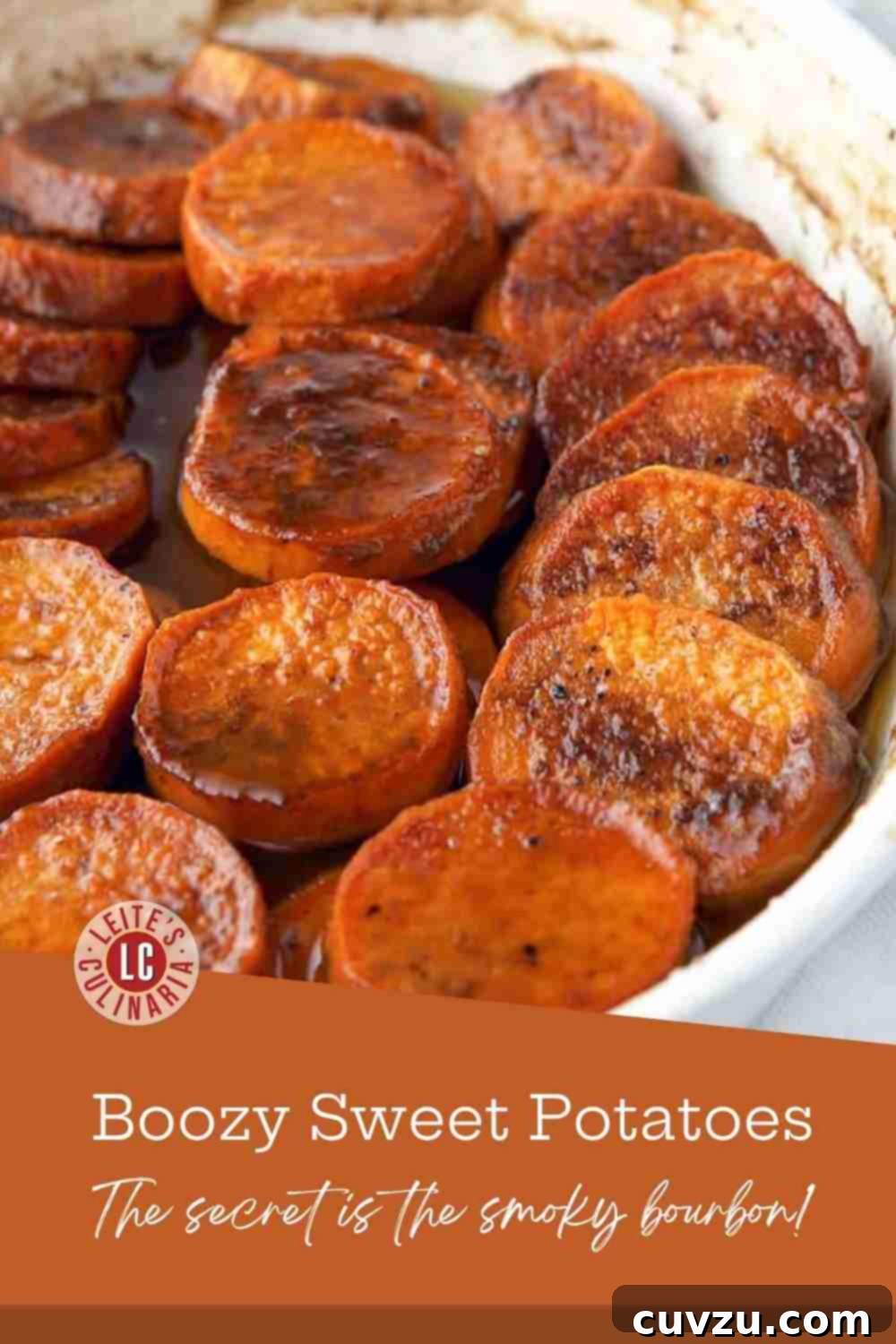 Bourbon Glazed Sweet Potatoes 3 Close-up of vibrant, caramelized sweet potato slices baked in a rich butter and bourbon glaze in a white oval baking dish, inviting a spoonful.
