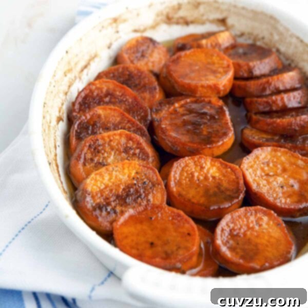 Bourbon Glazed Sweet Potatoes 4 Bourbon sweet potatoes in a white oval baking dish, sitting on a white and blue tea towel.