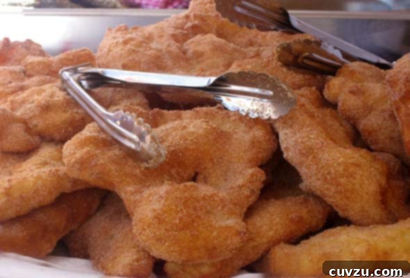 Malassadas Portugal's Golden Doughnut Delight 3 A pile of malassadas or Portuguese doughnuts with a pair of metal tongs
