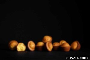 Portuguese mini lemon-orange cakes scattered on a black background with one torn in half.