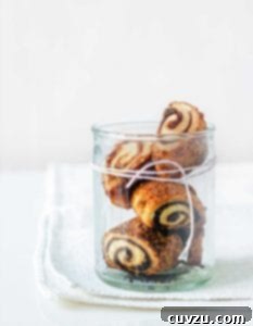 Four cream cheese rugelach in a glass jar with twine wrapped around it, showcasing their golden-brown perfection.