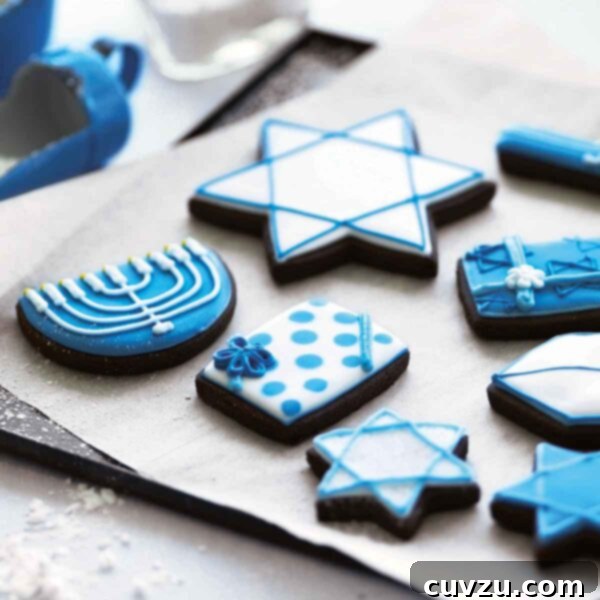A selection of frosted cookies decorated for Hanukkah, on a parchment-lined cookie sheet.