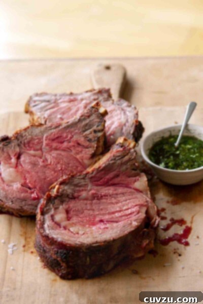 Three slices of medium-rare standing rib roast au jus on a cutting board, ready to serve.