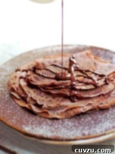 A stack of Tom Aikens' easy chocolate crepes, exquisitely prepared and ready to be enjoyed, hinting at the rich chocolate flavor within.