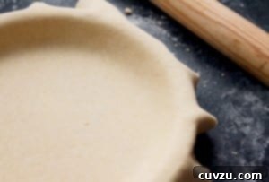 Classic Shortcrust Pastry 3 A golden Pâte Brisée crust draped in a pie plate, ready for filling, with a wooden rolling pin nearby.