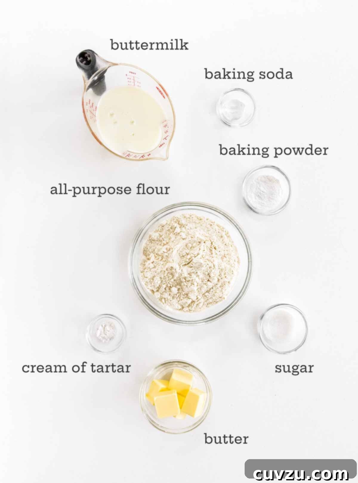 Ingredients for fluffy buttermilk drop biscuits, including buttermilk, baking soda, baking powder, all-purpose flour, sugar, cold butter, and cream of tartar.