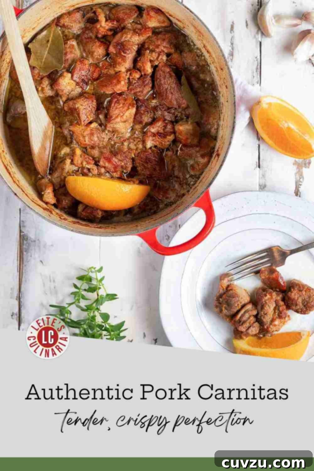 Crispy, tender pork carnitas served from a red pot with an orange wedge garnish and fresh herbs nearby.
