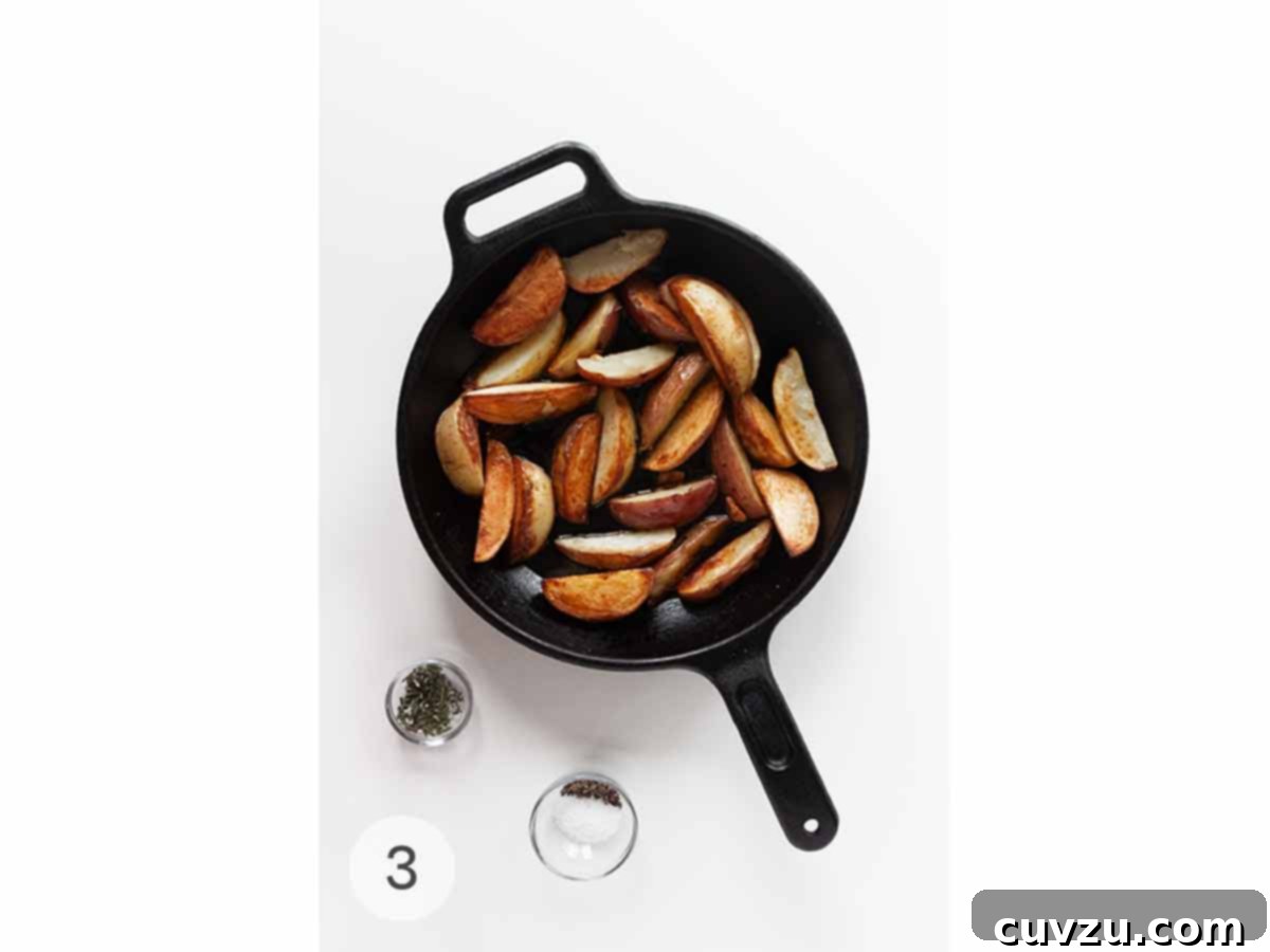 Smoky Golden Grilled Potatoes 6 A skillet of roasted grilled potatoes with a dish of chopped rosemary and a dish of salt and pepper beside it.