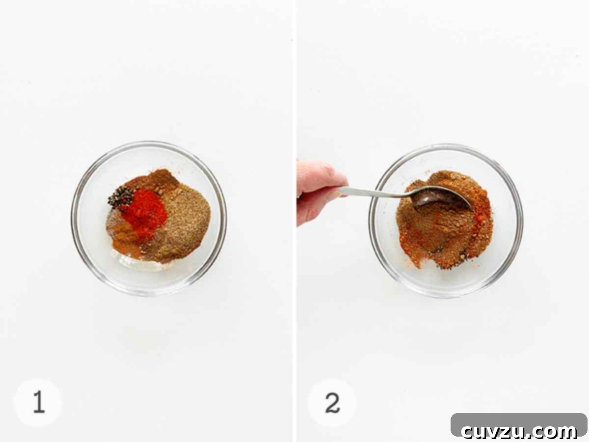 Craft Your Own Old Bay Seasoning 5 A person using a spoon to mix various colorful spices in a clear glass bowl, illustrating the straightforward process of making homemade Old Bay seasoning.
