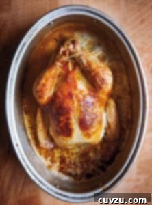 A whole cooked wheat beer roasted chicken in a deep oval baking dish.