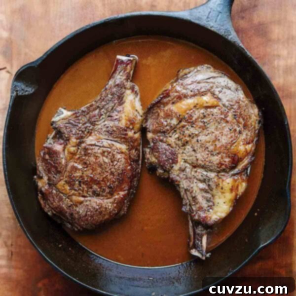 Guinness Smothered Cowboy Steaks 3 Two perfectly seared bone-in ribeye steaks resting in a rich, dark Guinness beer sauce, served in a rustic cast iron skillet.