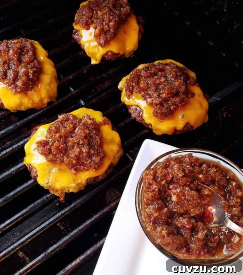 Smoky Sweet Bacon Reserve 3 Four delicious cheeseburgers on a grill, generously topped with homemade bacon jam, showcasing its perfect pairing.