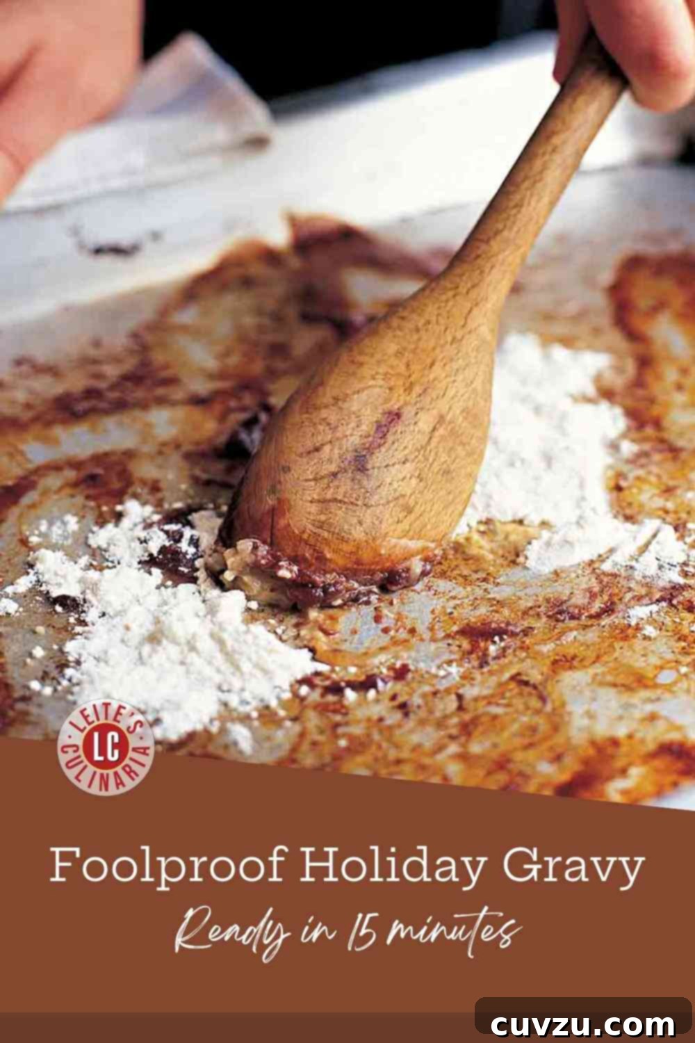 Classic Pan Gravy 3 A hand stirring a wooden spoon to blend white flour into dark brown, savory meat drippings and fat on a metal roasting pan.