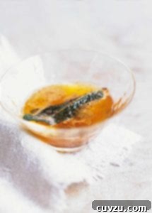 Sage brown butter with a crispy sage leaf in a small glass.