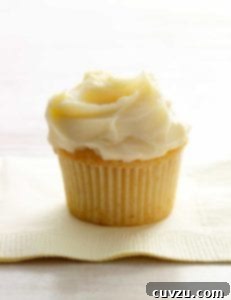 A single white chocolate cupcake, topped with white frosting on a paper napkin, illustrating the recipe.