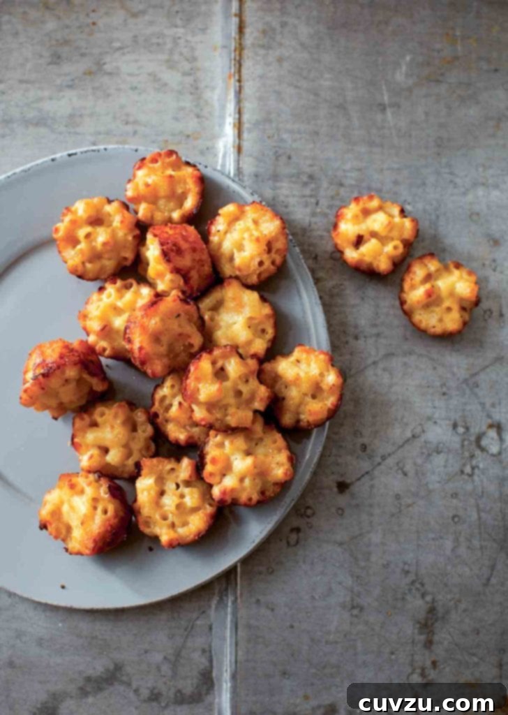 Mini Mac Bites 2 A grey plate half-filled with golden-brown mac and cheese canapés, with a few resting beside the plate, ready to be served at a party.
