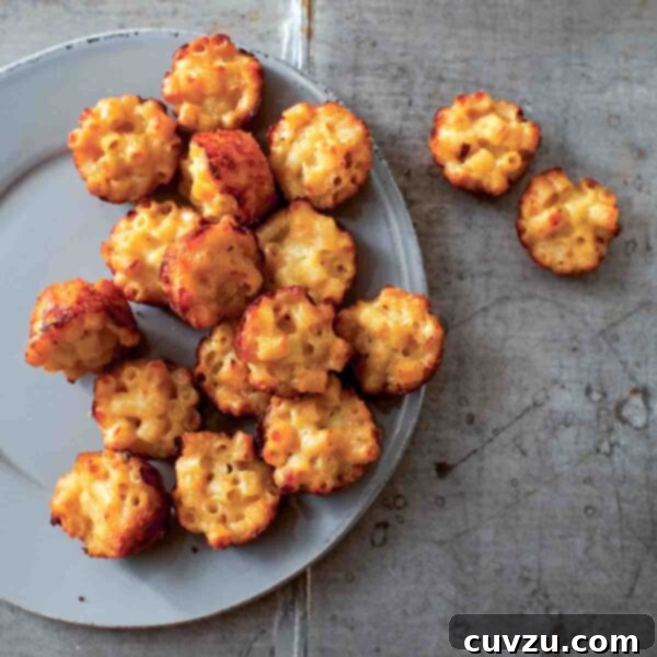 A grey plate half-filled with golden-brown mac and cheese canapés, with a few resting beside the plate, ready to be served at a party.