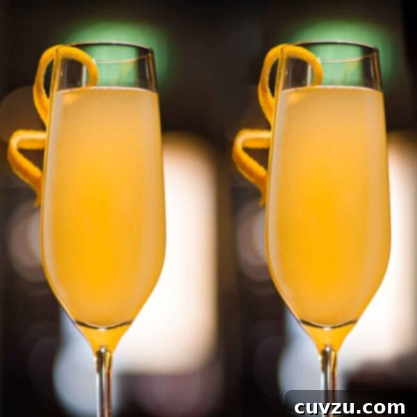 Two glasses of orange-colored Christmas cocktail with orange twists on the glasses, ready to serve.