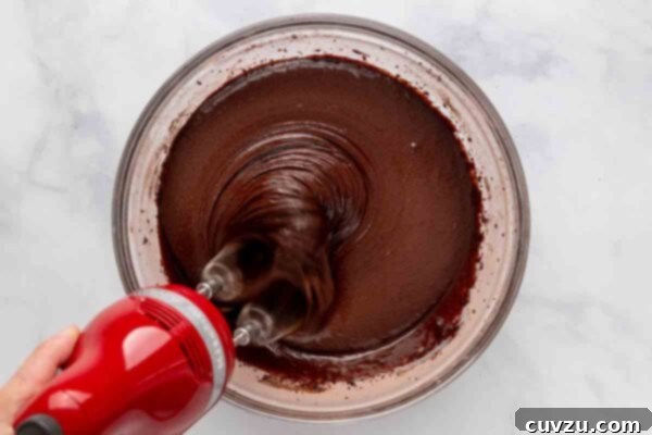 A hand mixer being used to beat cake batter.