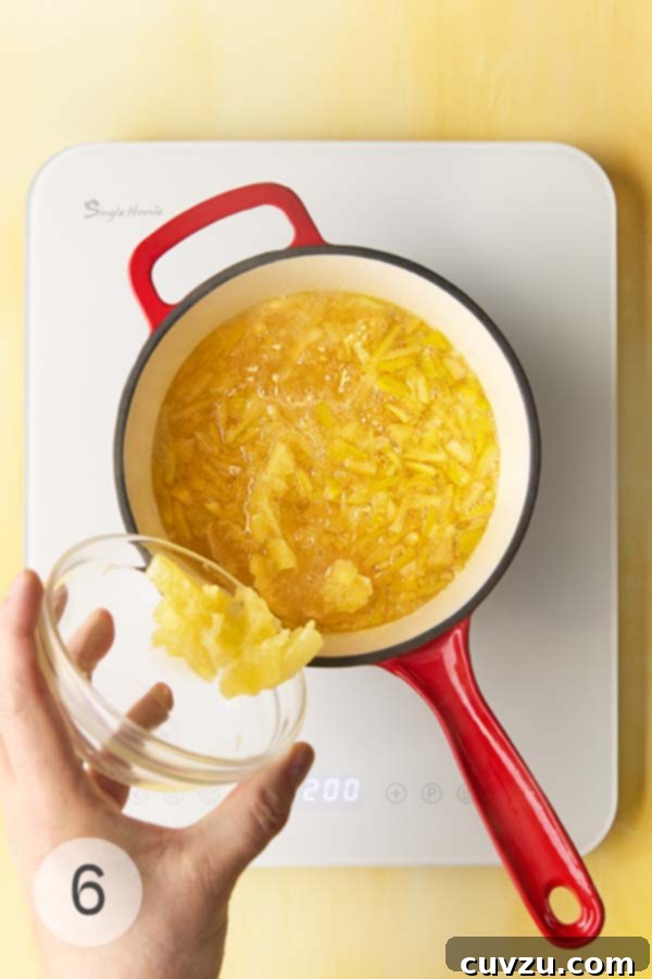 Fragrant Meyer Lemon Marmalade 12 A man's hand dumping Meyer lemon slices into a pot of lemon pieces simmering in sugar water.