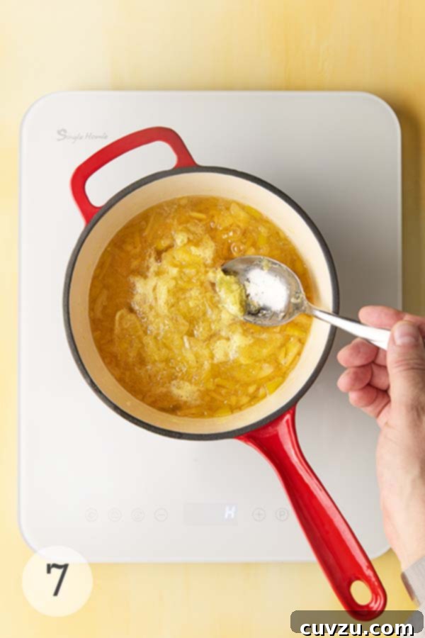 Fragrant Meyer Lemon Marmalade 13 A man's hand skimming foam from a pot of simmering Meyer lemon marmalade.