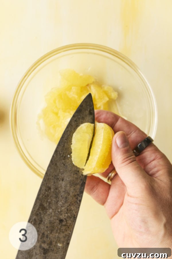 Fragrant Meyer Lemon Marmalade 9 A man'a hand slicing into a Meyer lemon, separating the fruit from the membrane.