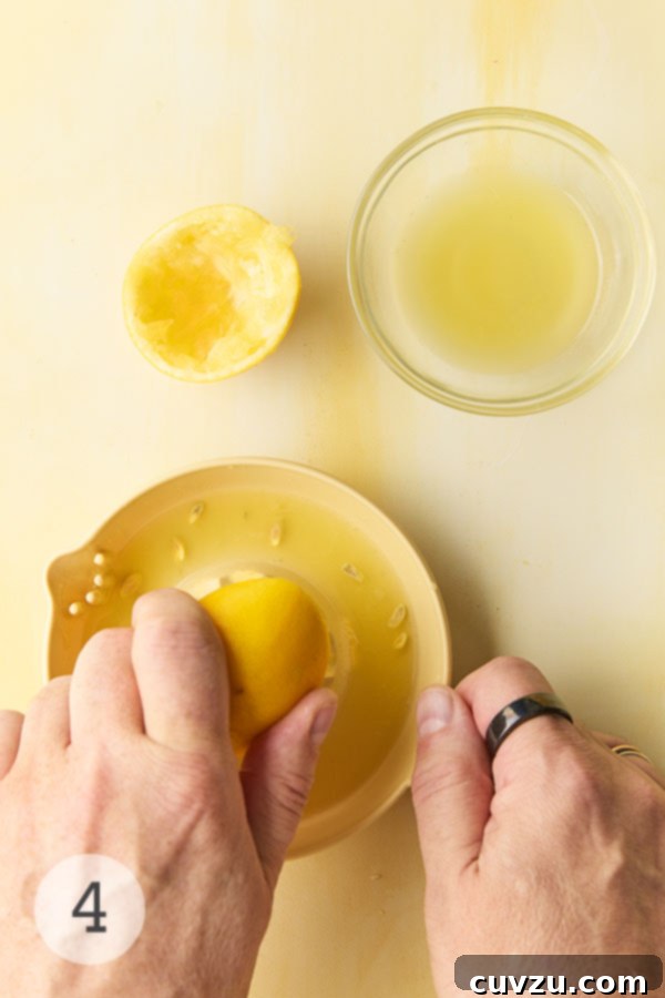 Fragrant Meyer Lemon Marmalade 10 A man's handing juicing a Meyer lemon half. Nearby is a glass bowl of lemon juice.