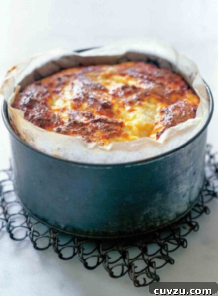 A parchment lined deep baking pan filled with baked ricotta, glistening and golden.