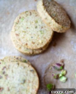 Emerald Pistachio Shortbread Delights 4 Five round pistachio shortbread cookies with a few broken pistachios on the side.