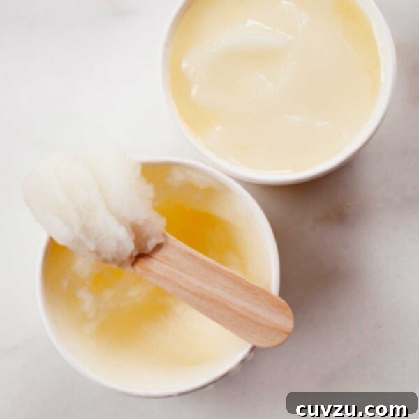 Zesty Frost 3 Two small bowls of lemon ice, with a wooden popsicle stick resting on top of one.