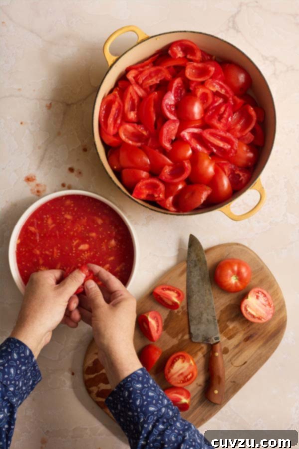 The Art of Homemade Tomato Paste 5 Hands removing seeds from quartered tomatoes over a white bowl, with a pot of seeded tomatoes nearby.