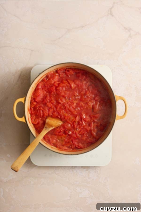 The Art of Homemade Tomato Paste 6 Chopped tomatoes boiling and softening in a large yellow pot to release their juices.