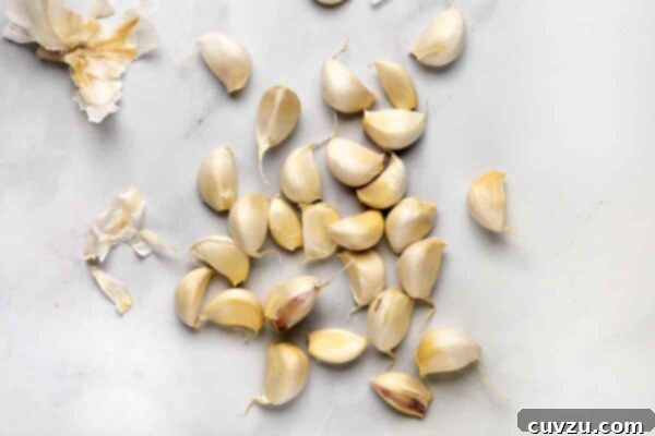 Golden Garlic Velvet 10 Loose garlic cloves with their husks nearby.