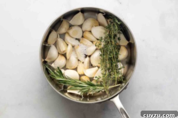 Golden Garlic Velvet 11 A pot filled with garlic cloves, thyme, and rosemary.