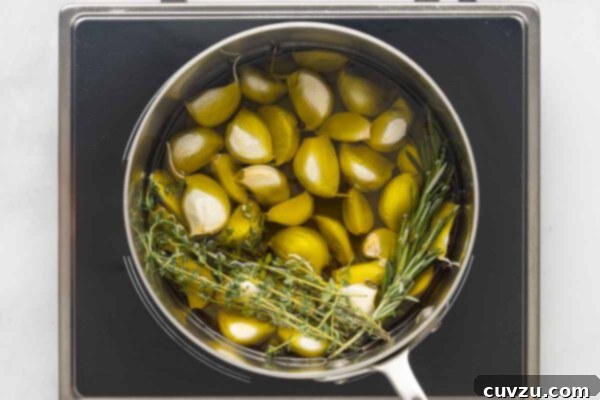 Golden Garlic Velvet 13 A saucepan of garlic, thyme, and rosemary and olive oil.