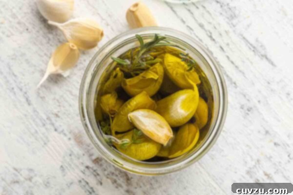 Golden Garlic Velvet 14 A jar of garlic confit with some loose garlic cloves nearby.