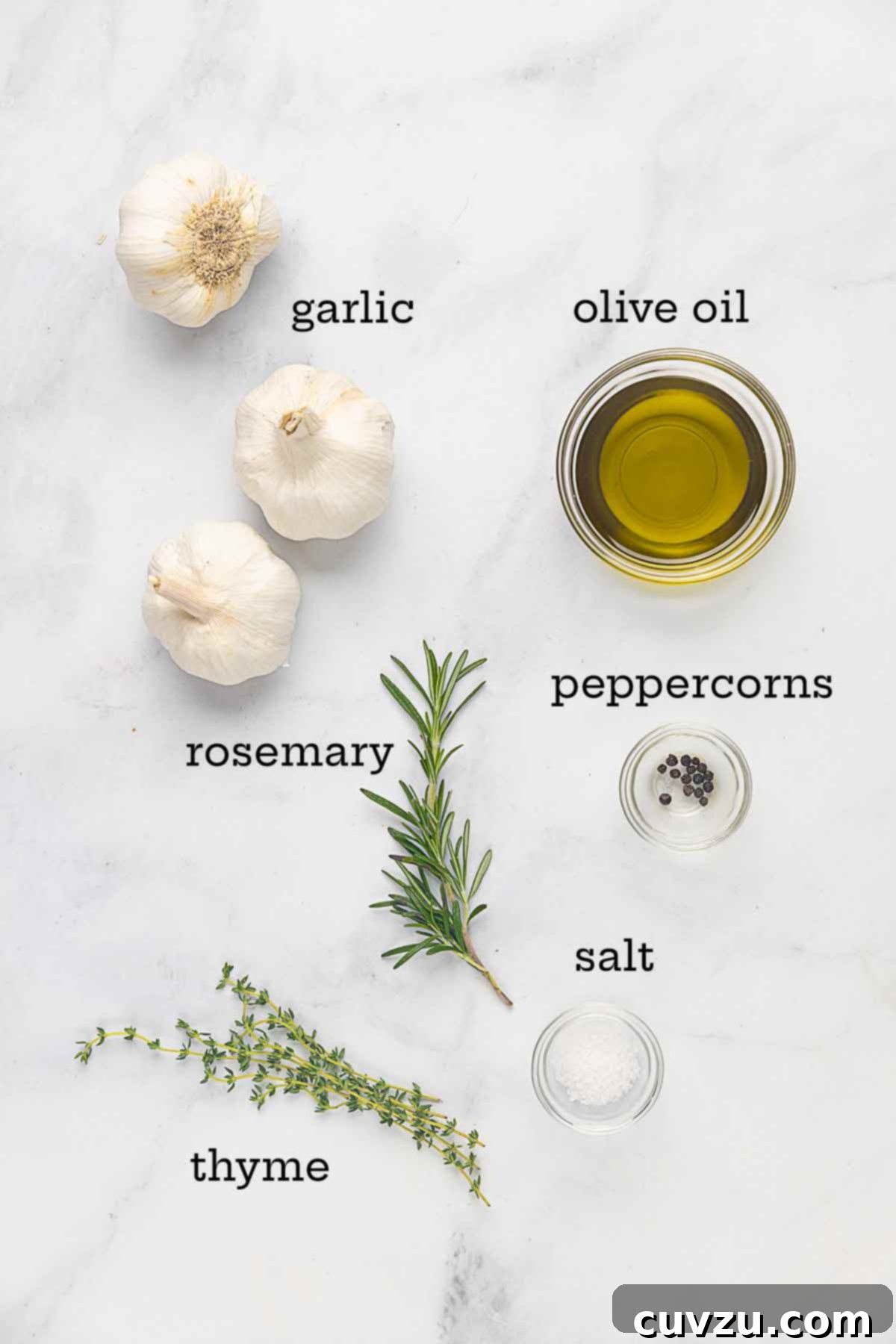 Golden Garlic Velvet 4 Ingredients for garlic confit arranged aesthetically: fresh garlic bulbs, sprigs of rosemary and thyme, black peppercorns, and a bottle of olive oil, ready for preparation.