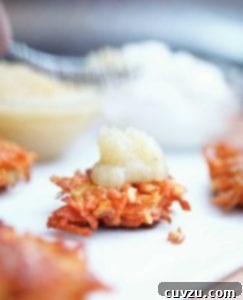 A root vegetable latke topped with a dollop of applesauce, symbolizing a healthy and delicious Hanukkah side dish.