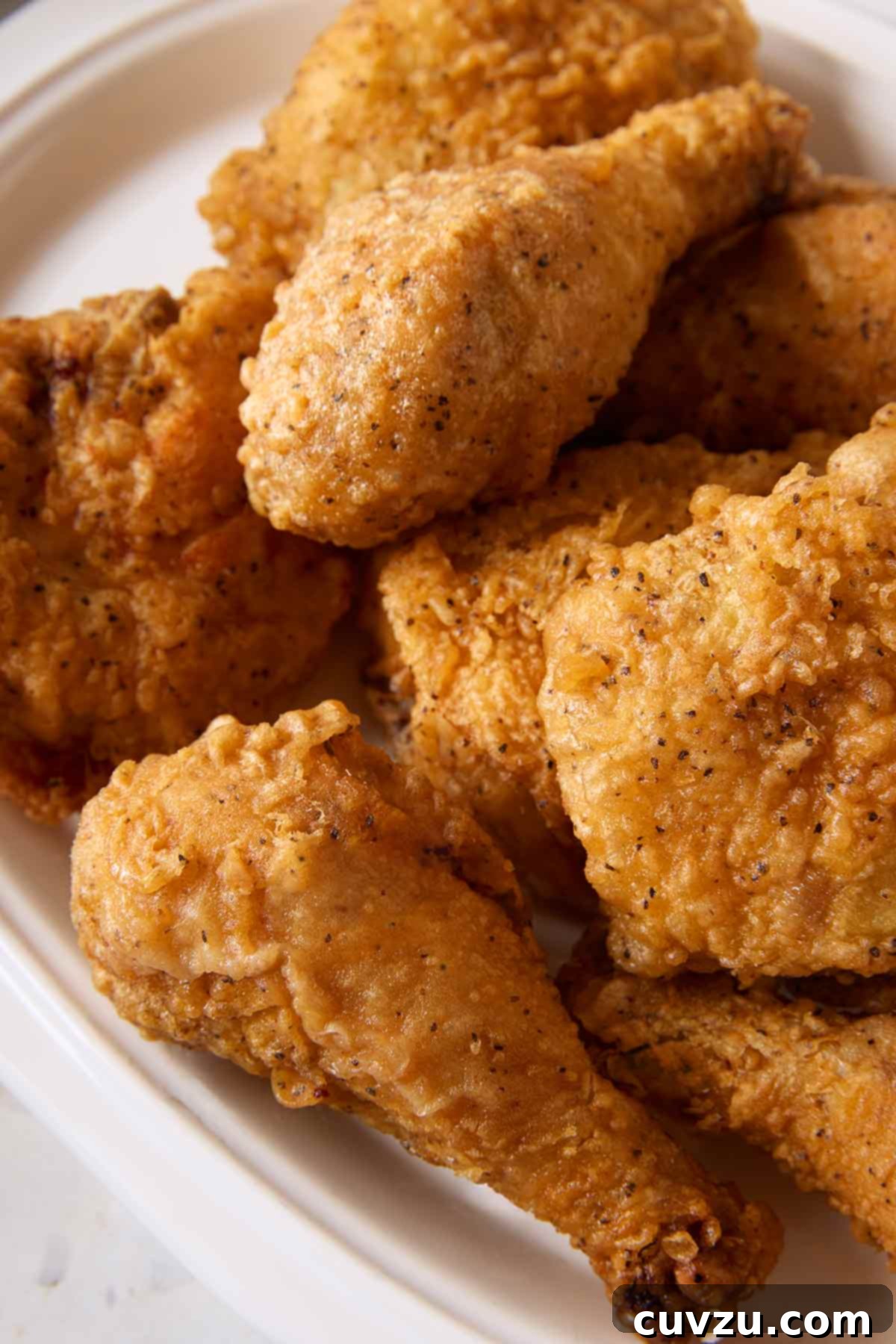 Effortless Extra Crispy Batter Fried Chicken 14 Pieces of batter-fried chicken piled on a white platter.