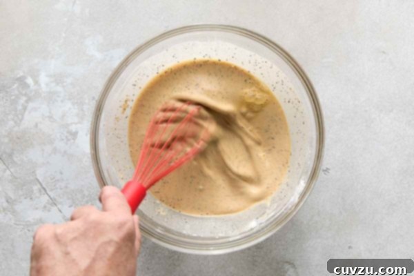 Effortless Extra Crispy Batter Fried Chicken 21 A person whisking a bowl of wet chicken batter.