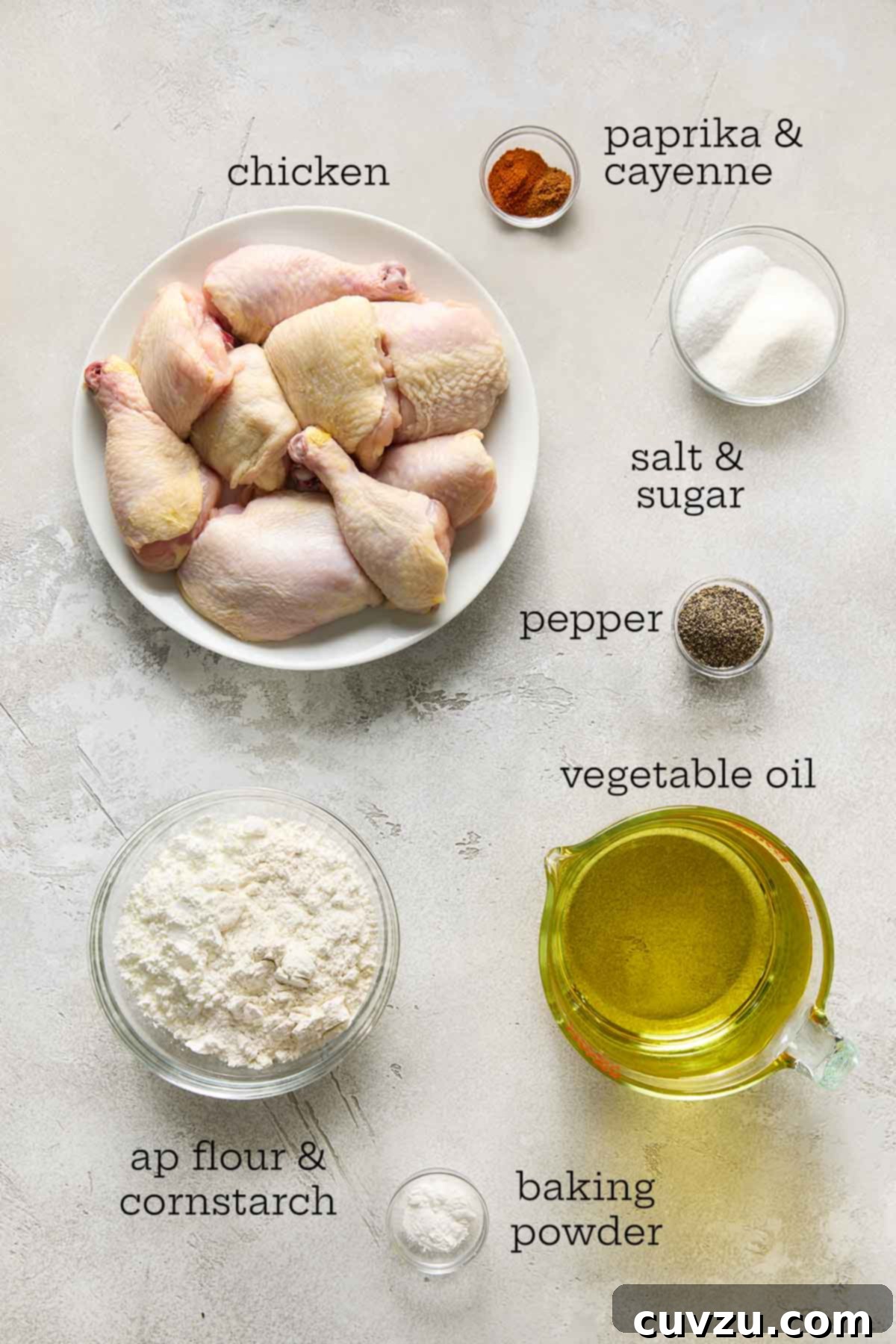 Effortless Extra Crispy Batter Fried Chicken 5 Ingredients for batter-fried chicken, including chicken, flour, spices, and oil, arranged on a counter.