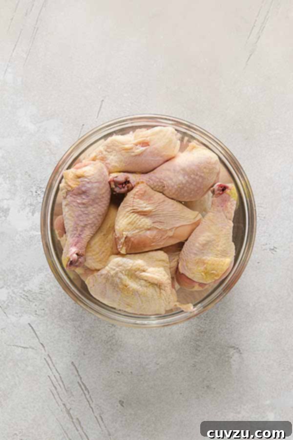 Effortless Extra Crispy Batter Fried Chicken 7 Raw chicken pieces brining in a saltwater solution in a large glass bowl.