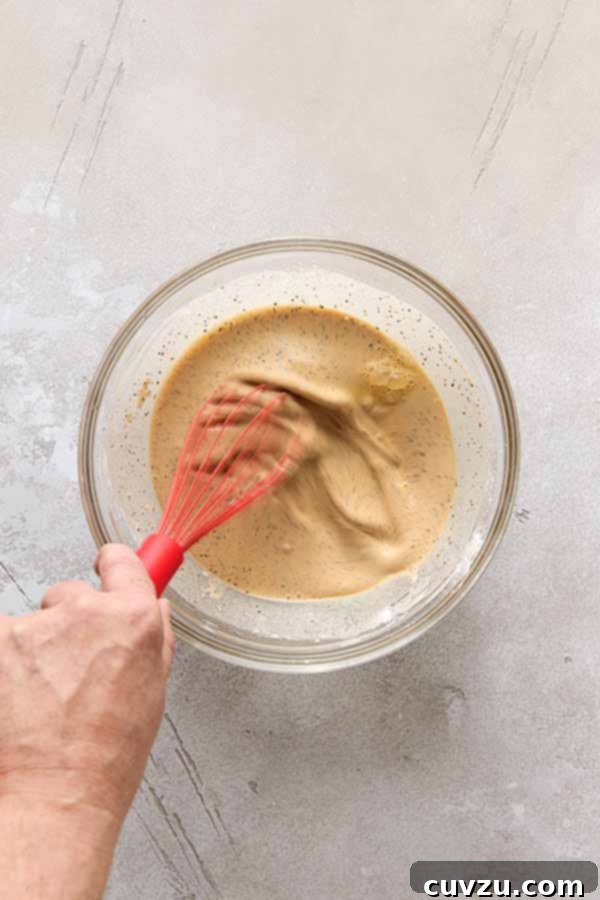 Effortless Extra Crispy Batter Fried Chicken 9 Whisking the wet and dry ingredients to create a smooth batter for fried chicken.