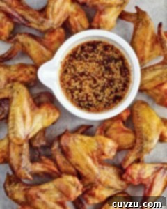 Korean chicken wings piled around a white container of dipping sauce.