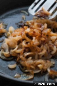 Slow Cooking Onions to Golden Perfection 3 A skillet with caramelized onions and a spatula moving the onions.