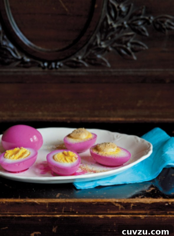 Tangy Egg Bites 3 A plate of pink pickled eggs, cut in half and smeared with spiced mayonnaise, showcasing their vibrant color and inviting texture.