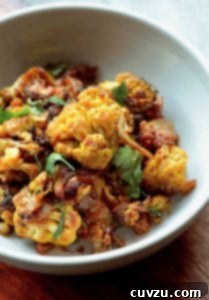 Curry-Kissed Roasted Cauliflower 3 A bowl of roasted curried cauliflower mixed with onions and topped with cilantro.