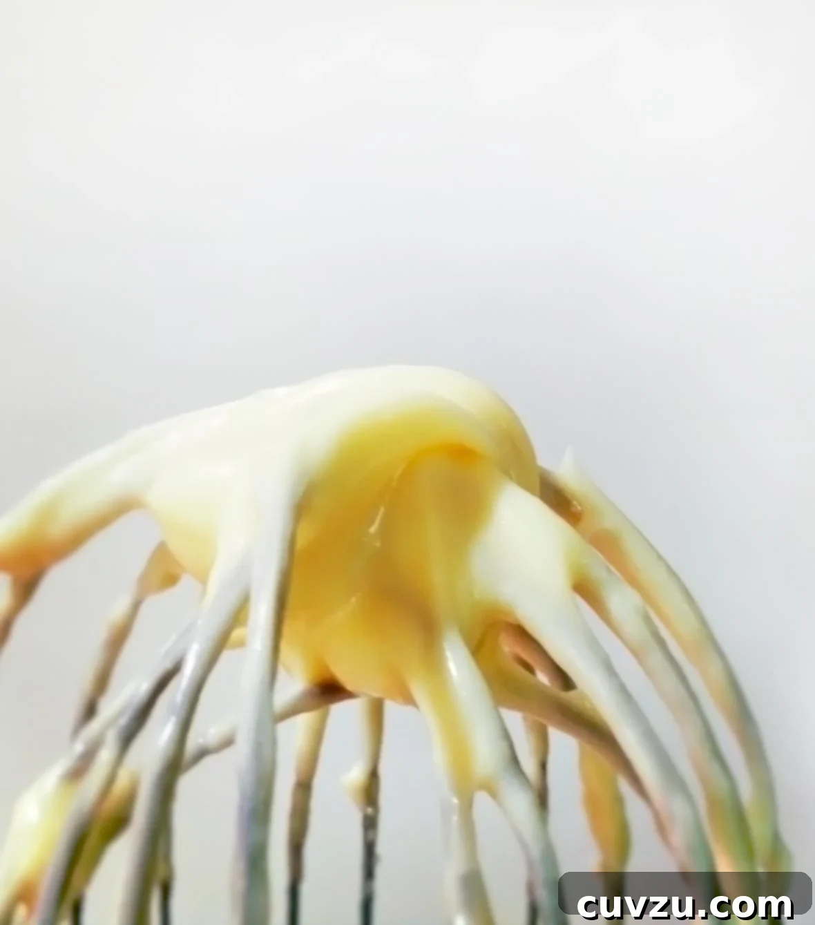 Whipping Up Your Own Mayo 2 A whisk coated with creamy, golden homemade mayonnaise, ready to be enjoyed.