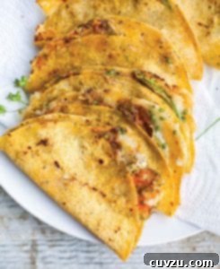 Six golden-brown squash blossom quesadillas, lightly stacked on a white serving platter, revealing the vibrant orange petals peeking out.
