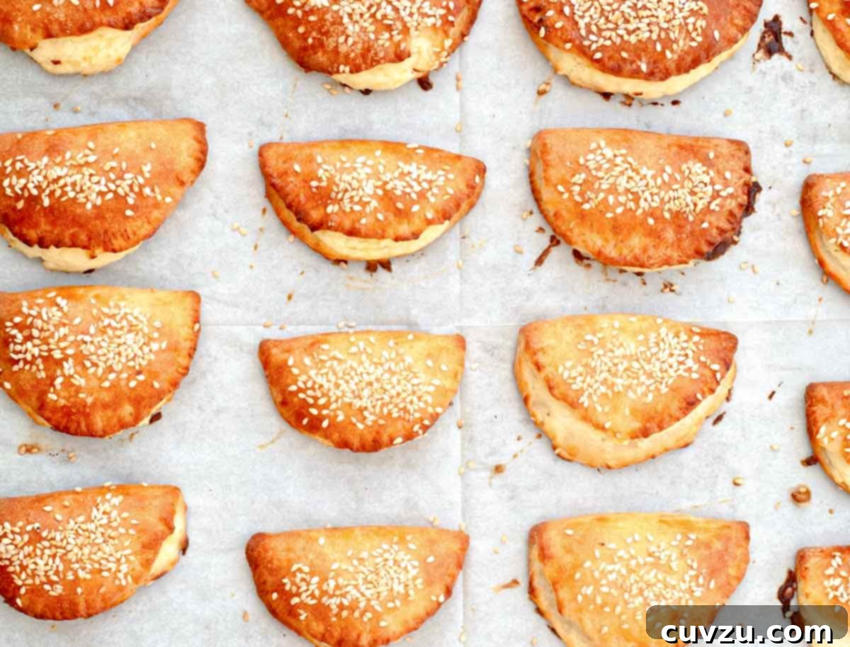 Golden Cheese Borekitas 2 Twelve Turkish borekitas sprinkled with sesame seeds on a piece of parchment.